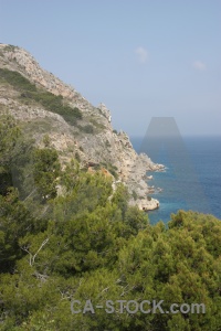 Tree rock sea spain sky.